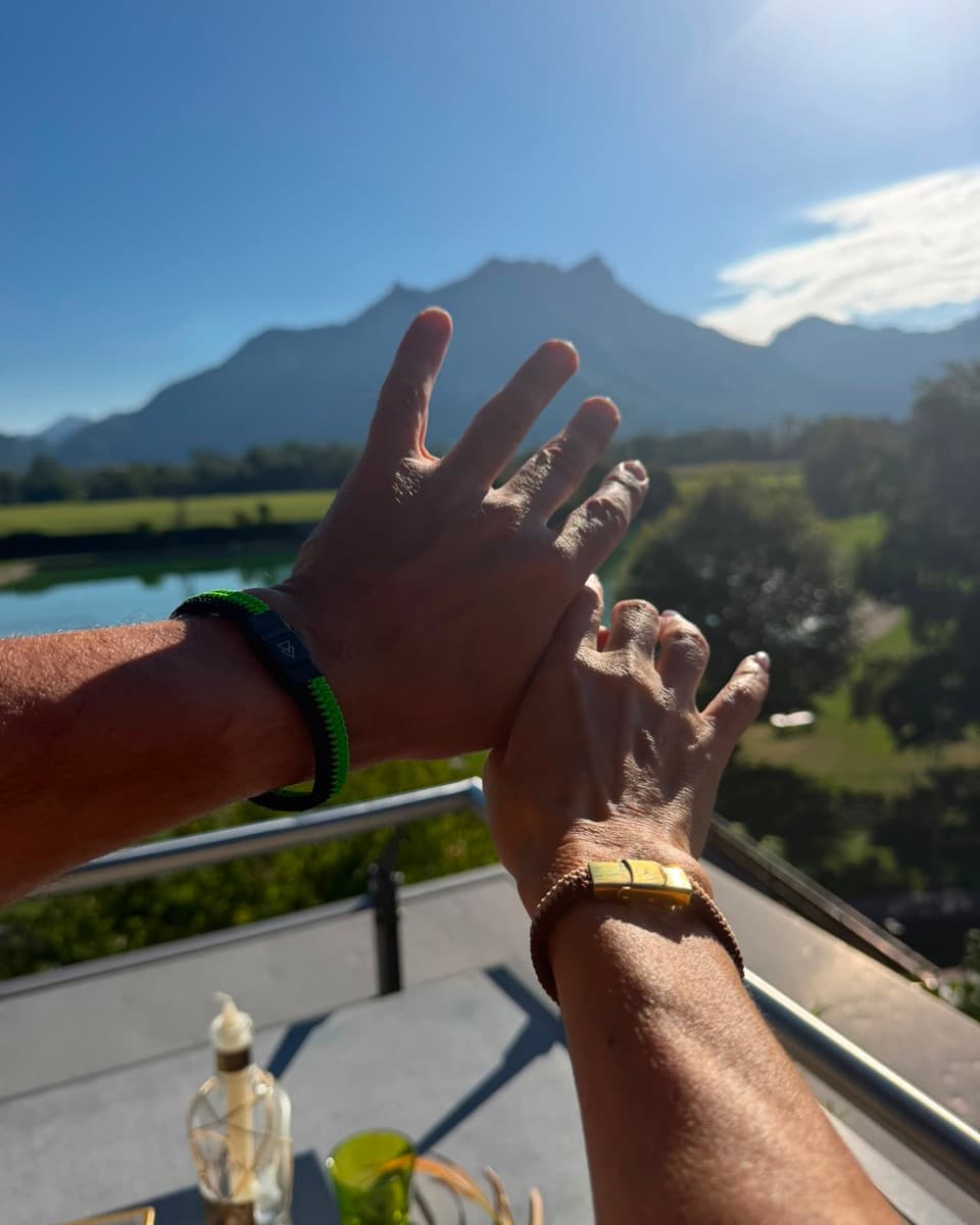 Zwei Arme mit den ersten Razelet-Bändern vor Bergen und See